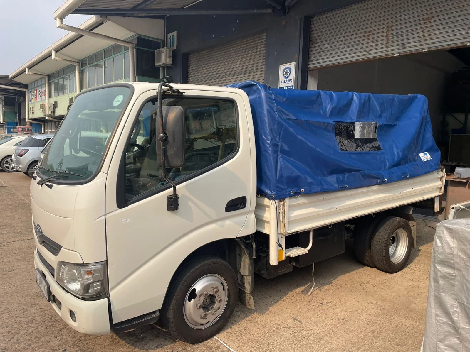 Real Minurphy build: a Toyota Dyna truck fitted with a custom blue PVC load tarp and clear viewing window, ready for transport